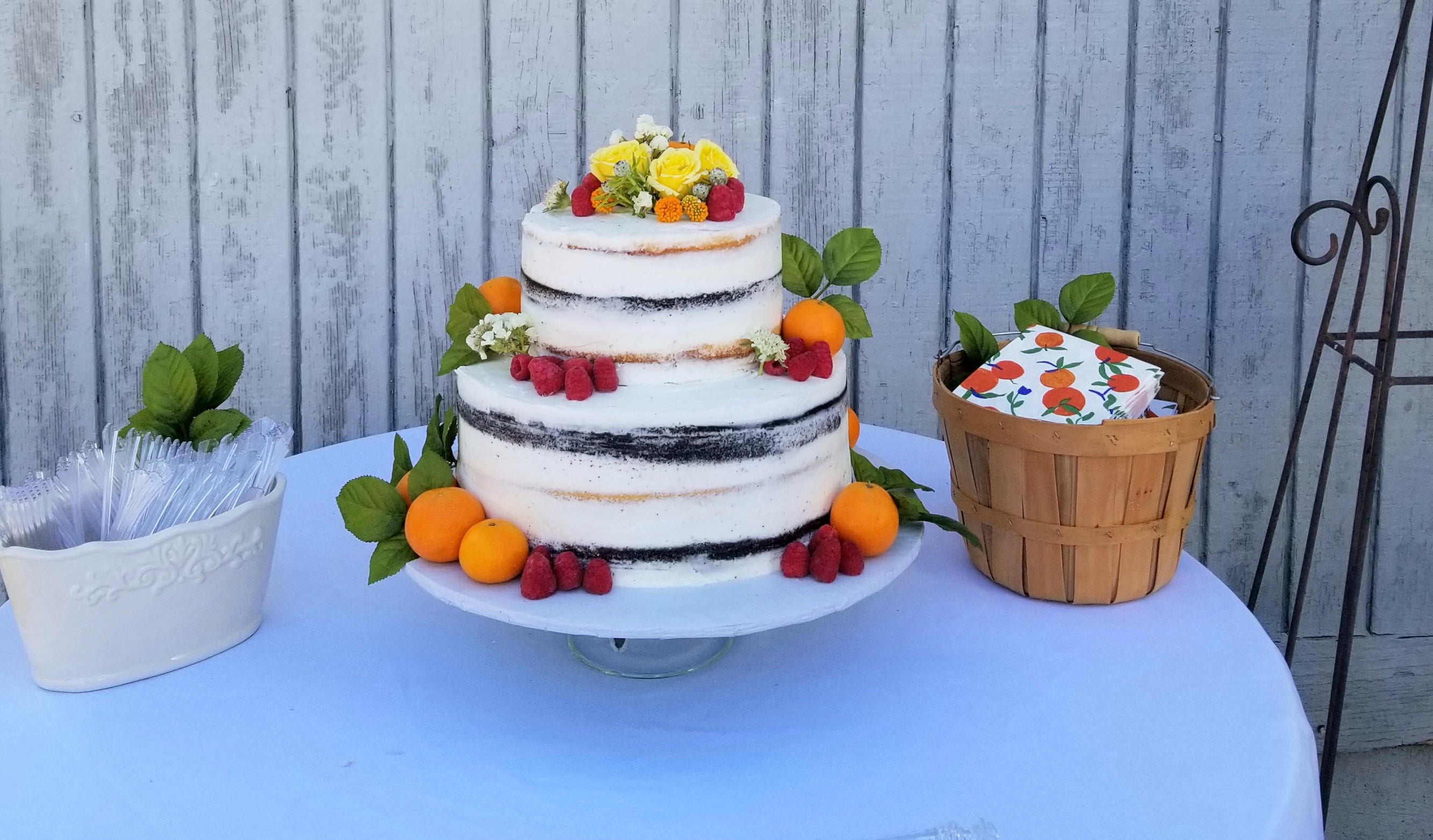 wedding cake with semi naked buttercream frosting and fresh berries, fruits and flowers