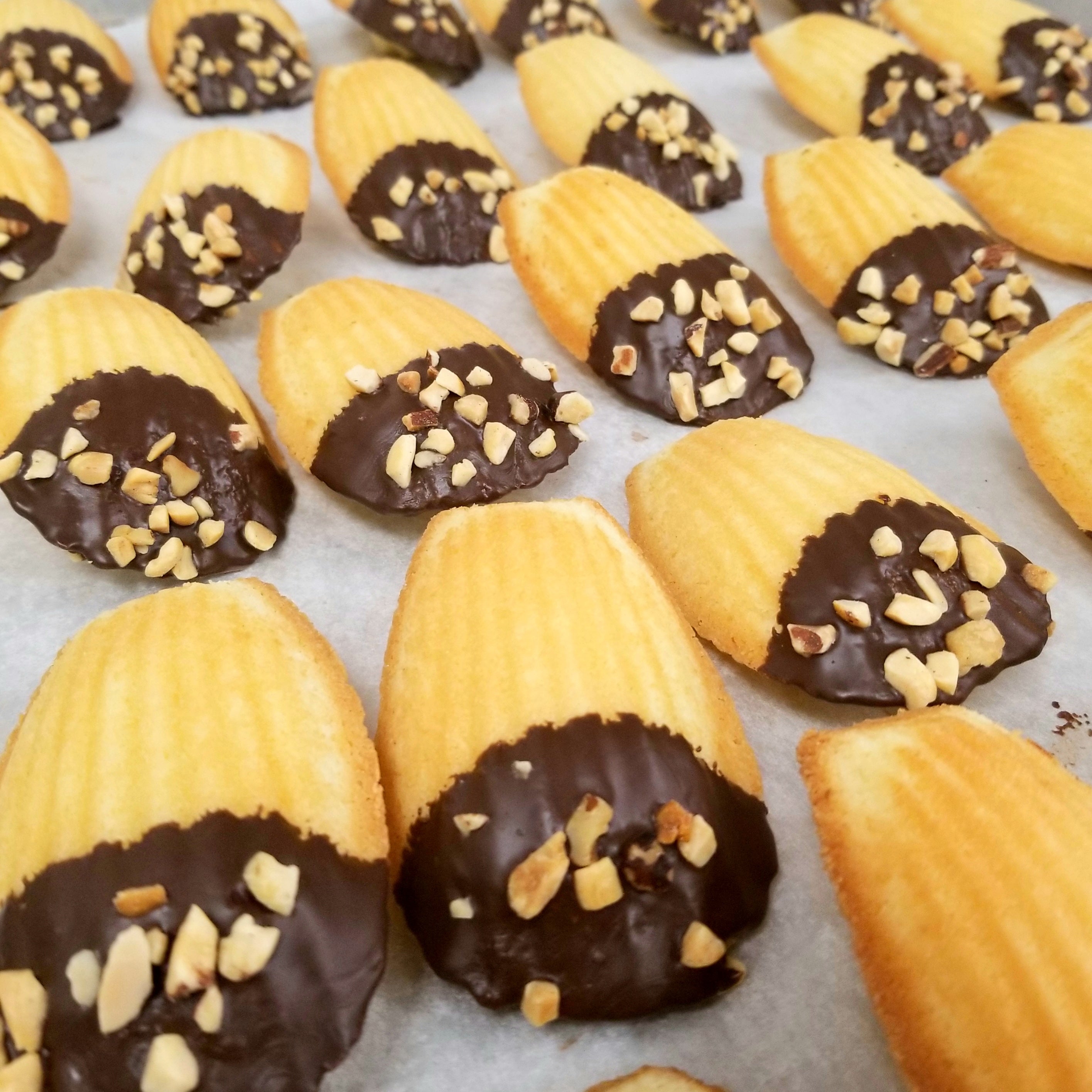 madeleine cookies dipped in chocolate topped with nuts