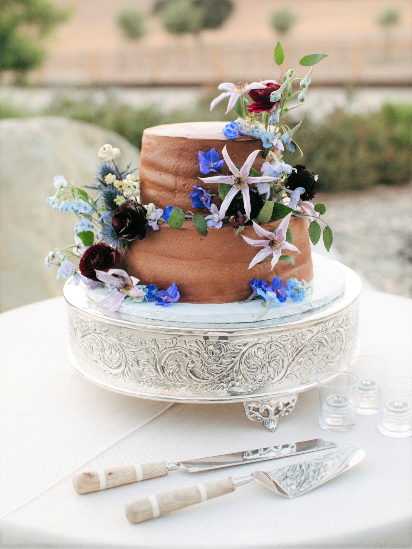 two tier wedding cake with chocolate buttercream frosting and fresh flowers